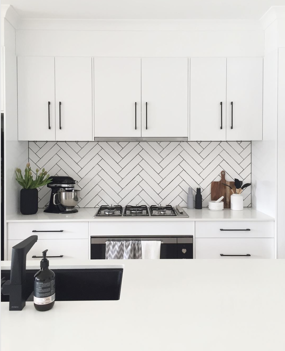White Shaker Kitchen With Black Hardware and Herringbone Tile Backsplash