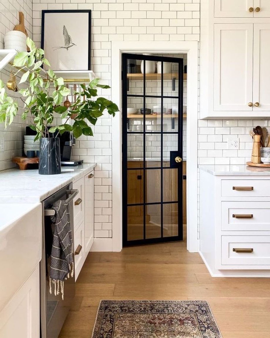 Kitchen With White Subway Tile and a Black-Frame Pantry Door